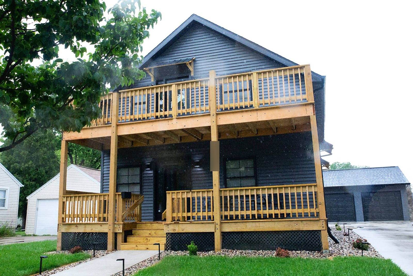 After: dark-sided Appleton duplex with two timber porch levels, front steps, lawn and a concrete path.